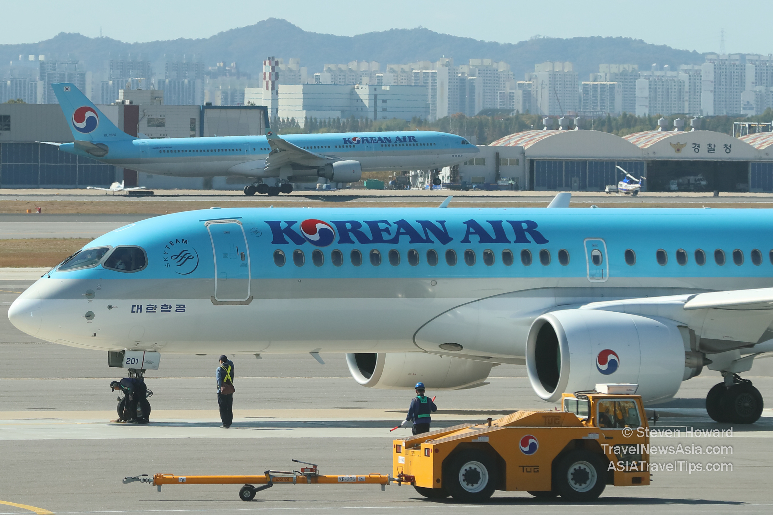 Korean Air A220-300 reg: HL7201 aircraft in the foreground and a Korean Air Airbus A333 reg: HL7524 taking off in the background. Picture by Steven Howard of TravelNewsAsia.com Click to enlarge.
