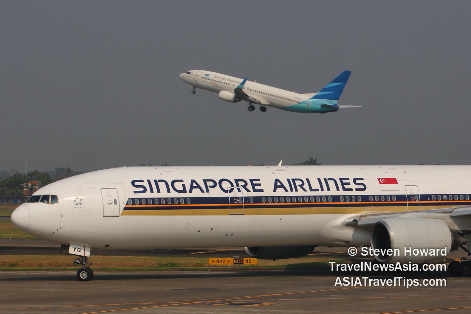 Singapore Airlines B777 in foreground with a Garuda Indonesia aircraft taking off in the background. Picture by Steven Howard of TravelNewsAsia.com Click to enlarge.